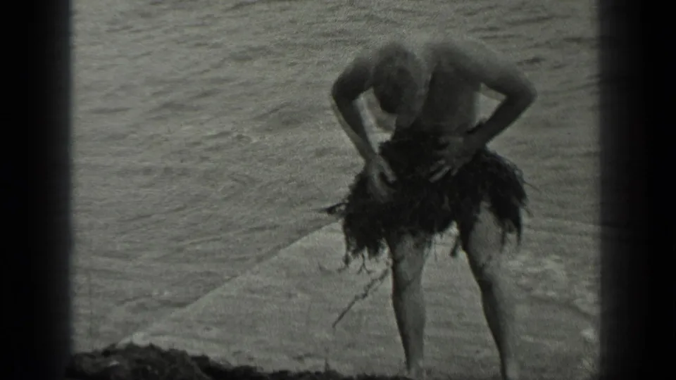 In 1939 Long Lake, Canada home-movie footage, a shirtless man stands by the water adjusting seaweed around his waist.
