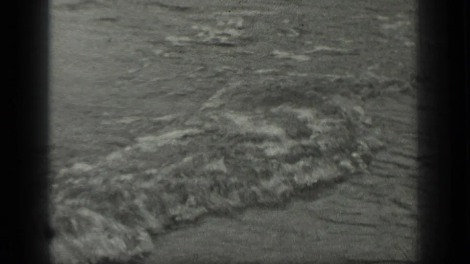 The frame settles on Long Lake water and a foamy wave pattern near shore, with no clear figure visible in this extracted still.