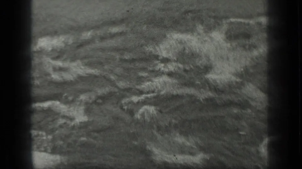 1939 Long Lake, Canada home-movie frame showing a breaking wave with white foam over dark wet sand.