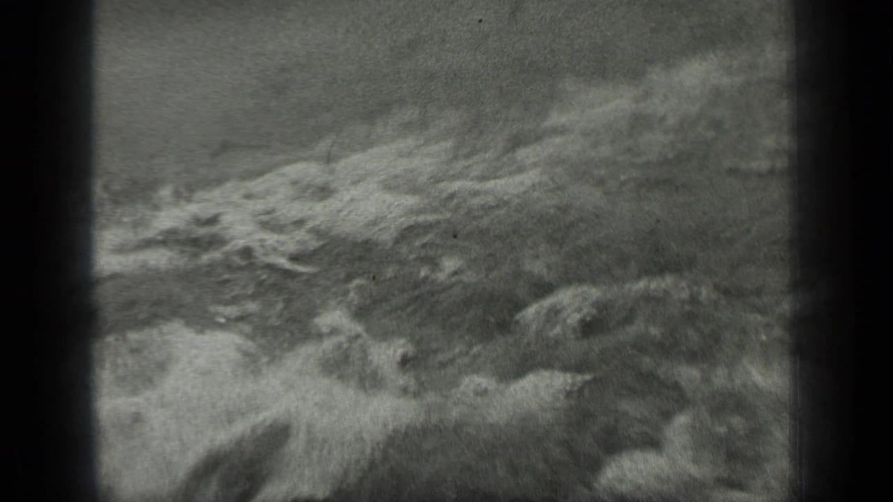 Foamy waves breaking across a dark lake surface near shore.