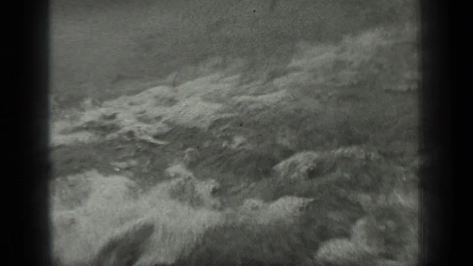 Black-and-white 1939 Long Lake footage showing rough foamy water moving toward the shoreline.