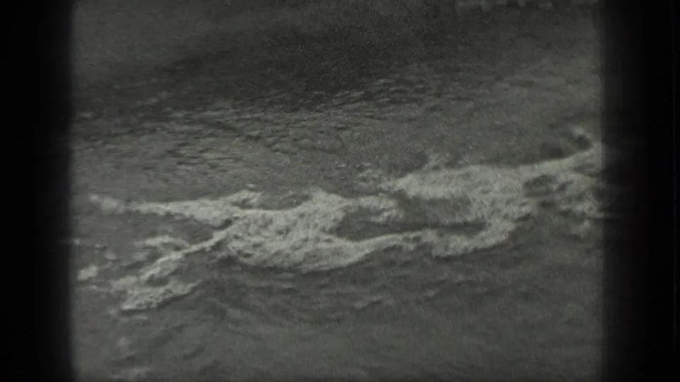 Black-and-white 1939 Long Lake frame with white foam streaking over choppy water close to shore.