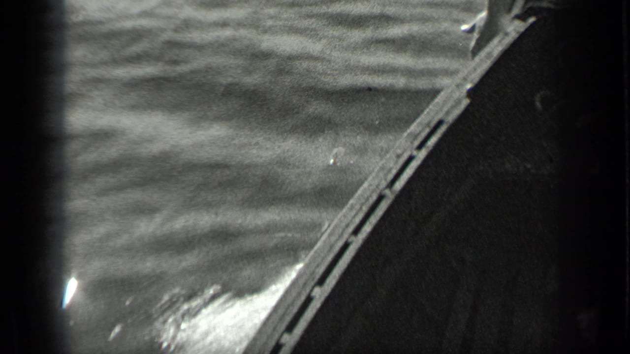 Bow edge of a small boat cutting through rippling lake water.