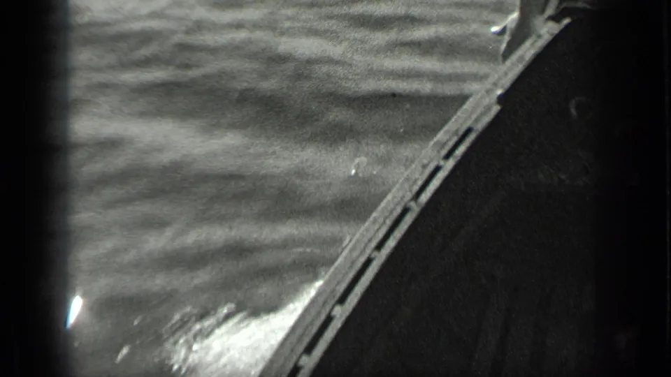 1939 Long Lake, Canada home-movie frame showing the side of a small boat moving through rippling water.