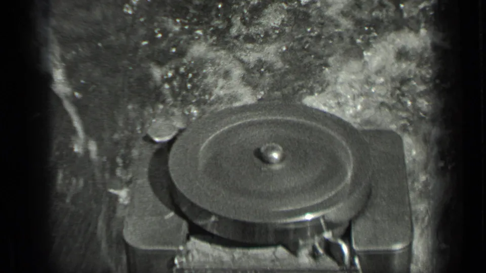 Close 8mm frame of a round engine or mechanical component with water churning nearby on the small boat.
