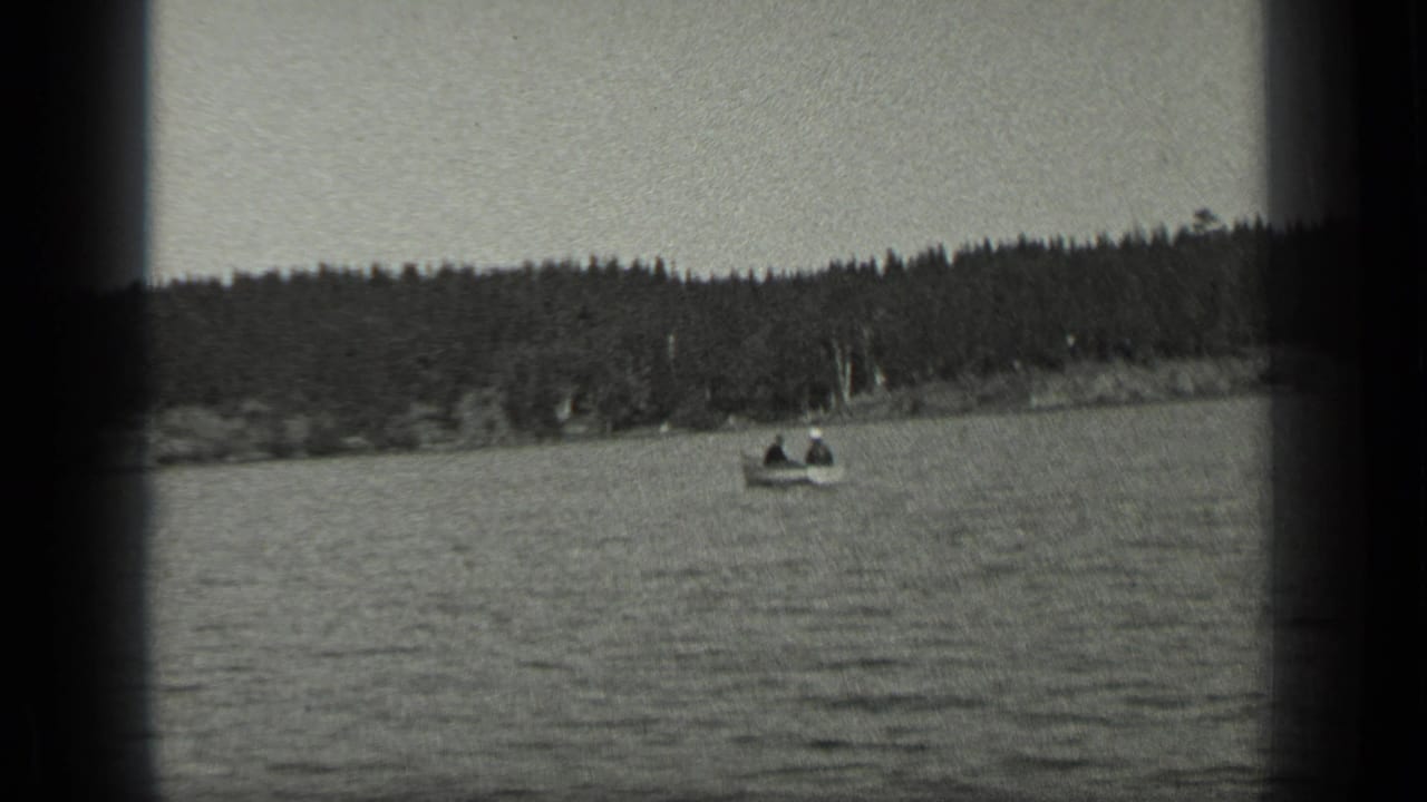 Wide lake view with small boats and a wooded shoreline in the distance.