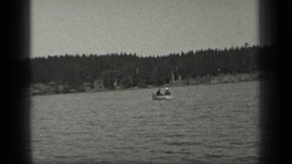 Black-and-white 1939 home-movie frame from Long Lake, Canada, showing open water, small boats, and a tree-lined shore.