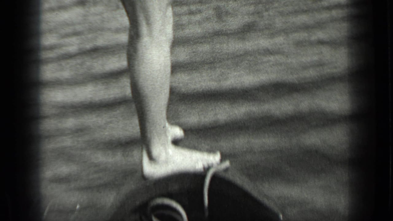 Bare feet and lower legs standing on the edge of a small boat over rippled water.