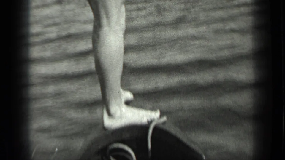 Close 1939 8mm view at Long Lake, Canada, showing a man’s bare feet and lower legs on a boat above rippled lake water.
