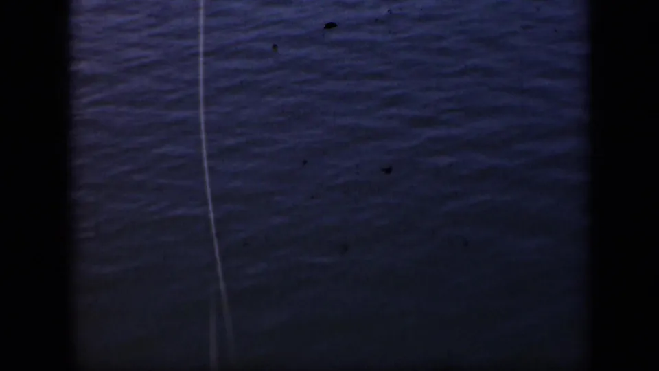 1948 Long Island 8mm frame showing rippled water and a taut fishing line, with visible film borders and dust specks.