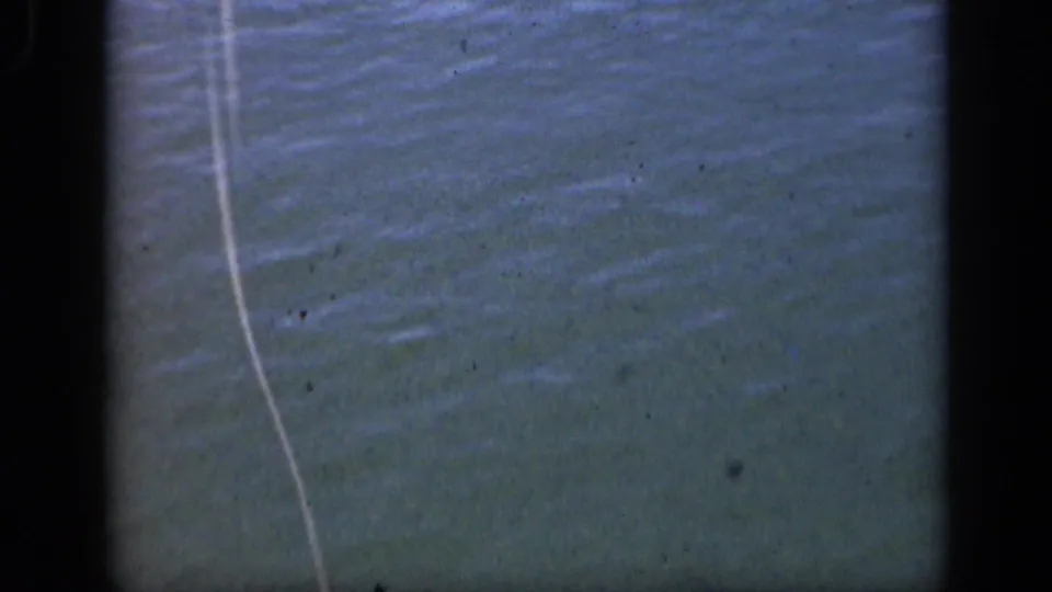 Close 8mm view of a fishing line over Long Island water, with soft focus, grain, and dark frame edges.