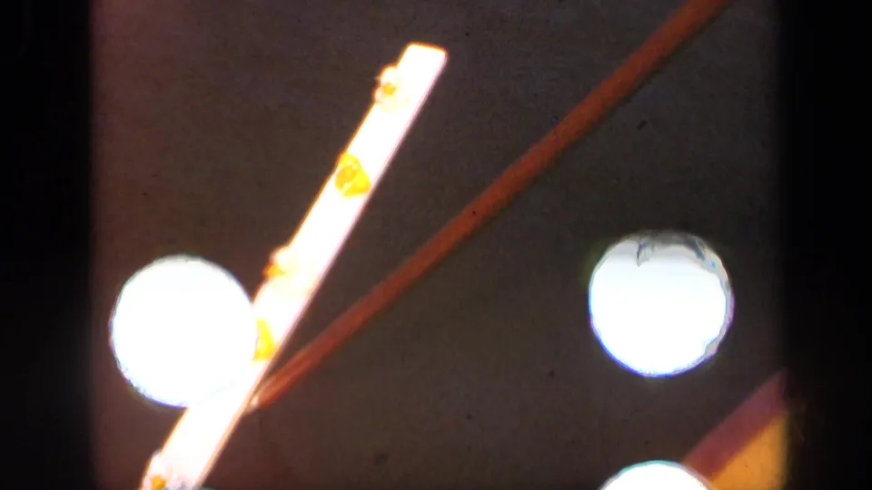 Final 1948 Long Island frame showing the white and yellow object, diagonal brown rod, and bright circular light spots in soft exposure.