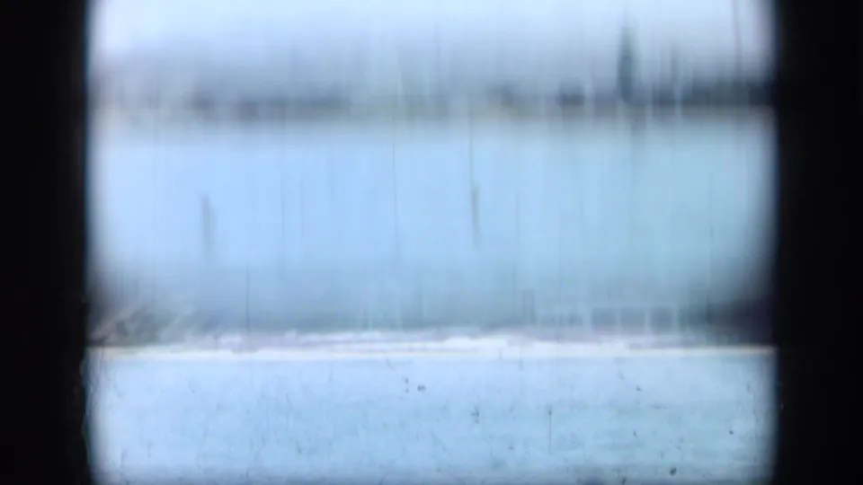 Hazy 1948 Long Island shoreline view with pale water, beach, and heavy film wear framed by dark gate edges.