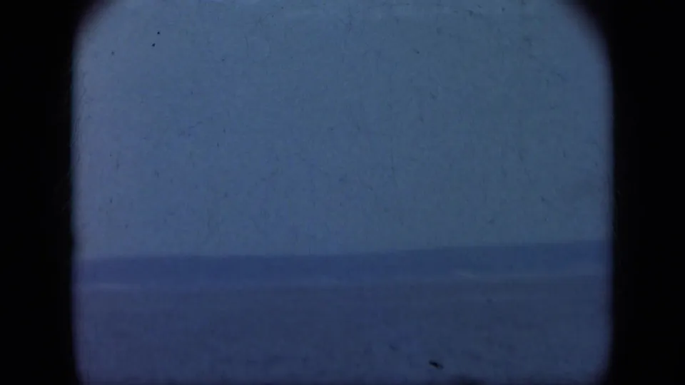1948 8mm coastal view from Long Island showing calm water and a low distant landform beneath an overcast sky.