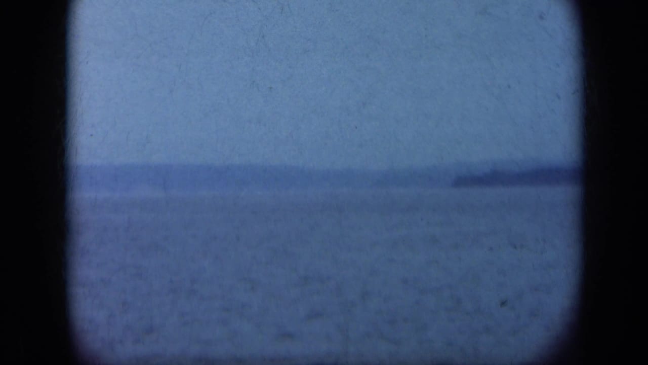 1948 Long Island home-movie frame showing calm water, hazy sky, distant shore, and dark rounded film-gate borders.