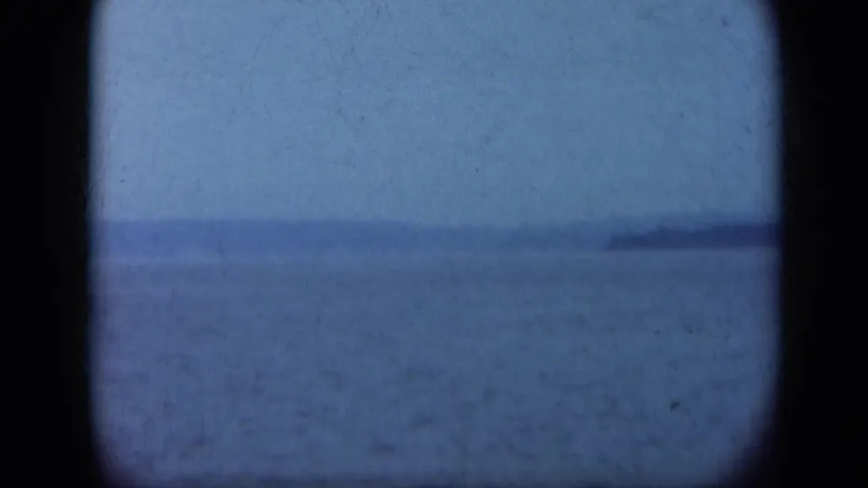 1948 Long Island home-movie frame showing calm water, hazy sky, distant shore, and dark rounded film-gate borders.