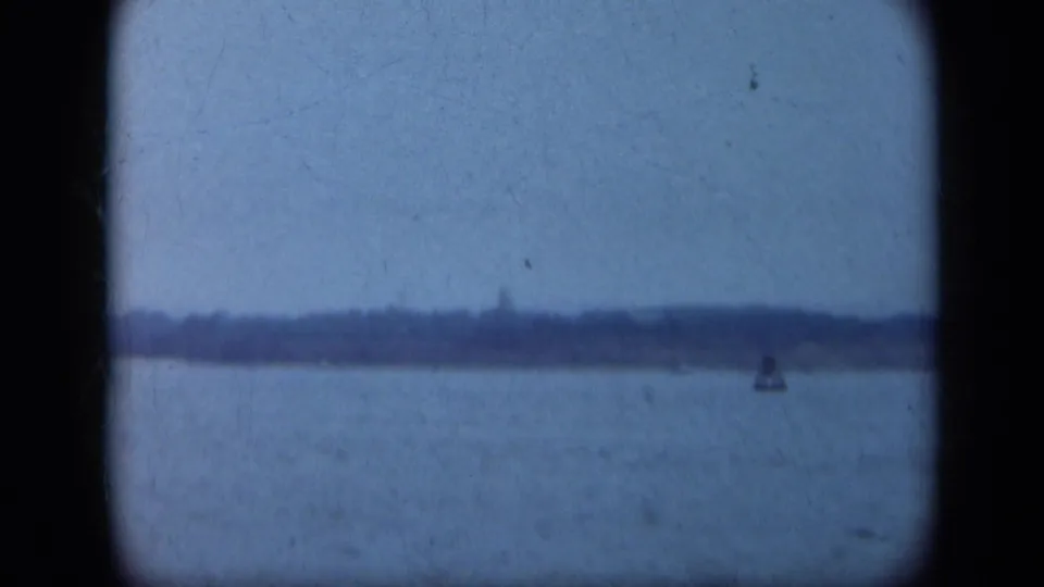 1948 Long Island water view with a faint shore on the horizon and a small indistinct object on the right, seen through 8mm gate edges.