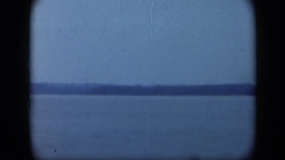 A soft 1948 Long Island shoreline view shows calm water, pale sky, and rounded 8mm frame edges with visible film texture.