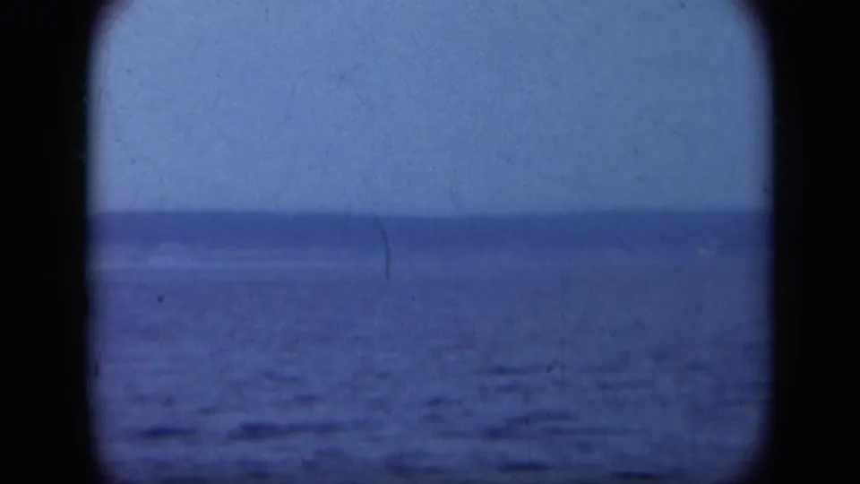 Soft 1948 Long Island boat view with calm water, hazy sky, and a low shoreline barely visible beyond the frame edge.