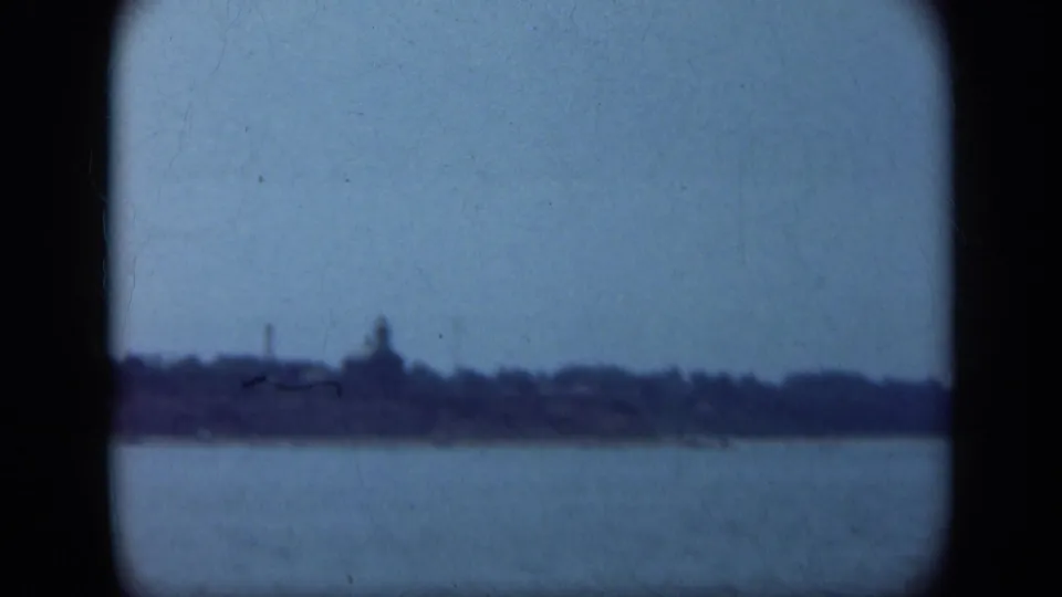 1948 Long Island home-movie frame showing water and a distant shoreline, viewed through a soft, dark-edged 8mm image.