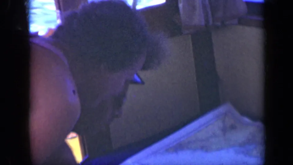Dim 1948 shipboard interior near Long Island with an adult man leaning toward a spread chart under cool blue light.