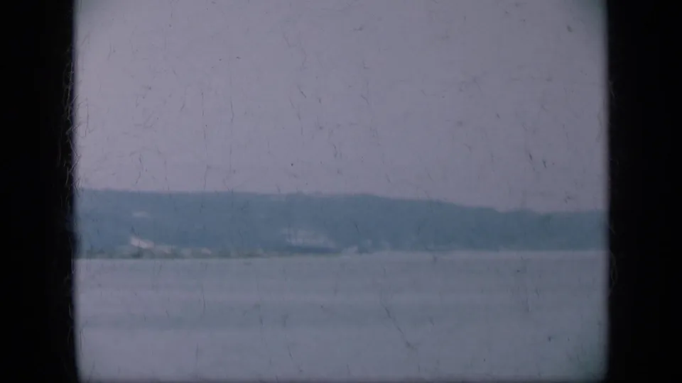 Long Island coastal water seen through a window, with a dark frame dividing the hazy shoreline view.