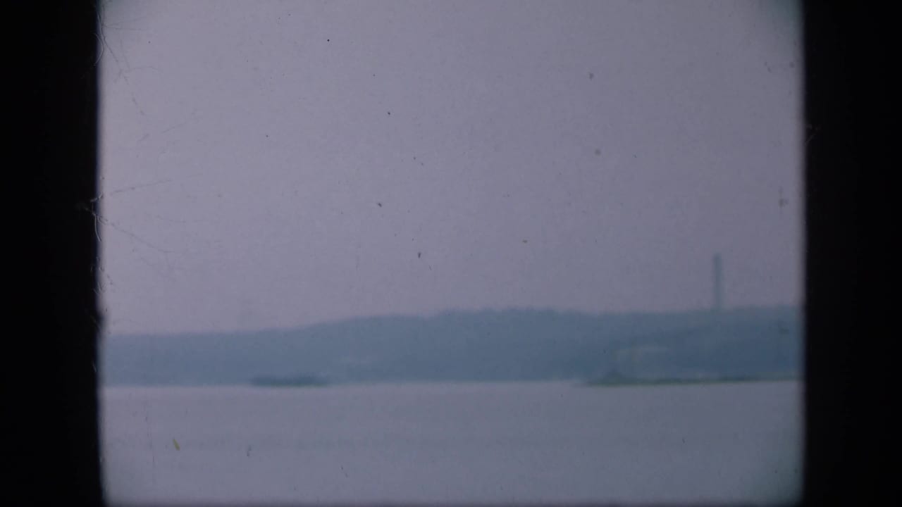 Hazy water and distant shoreline seen through dark vertical borders.