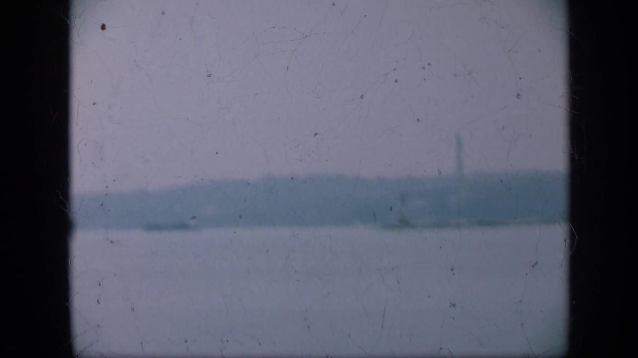 Distant shoreline across water under a pale hazy sky.