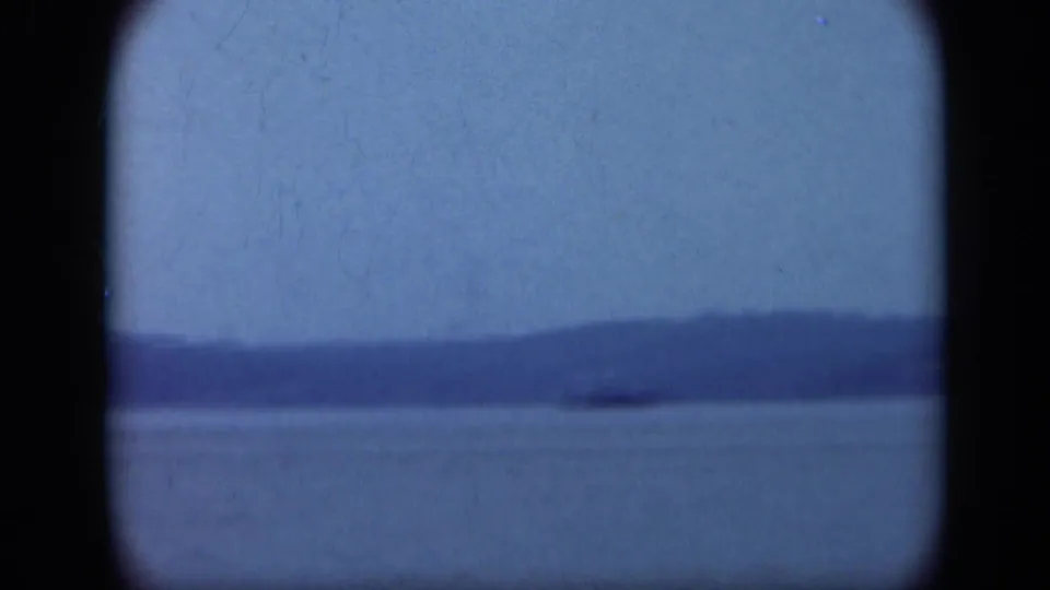 1948 Long Island shoreline footage showing a wide expanse of water, distant low hills, soft blue sky, and dark 8mm frame borders.
