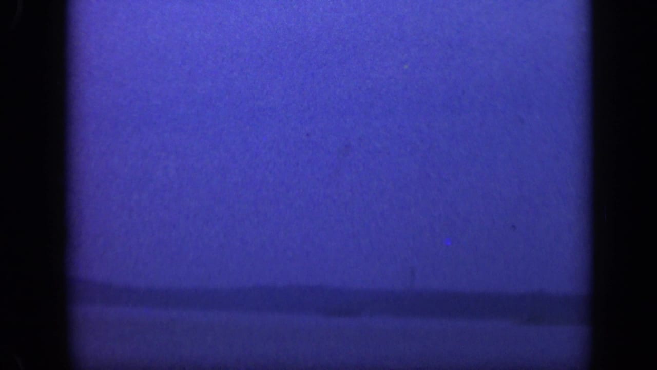 Blue-toned ocean horizon with dark film edges and a soft, grainy sky.