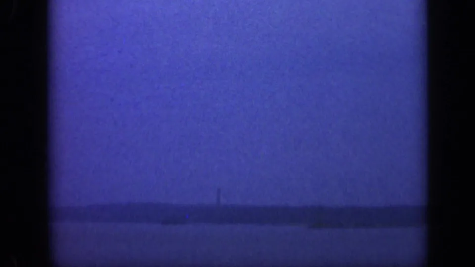 Blue-tinted 1948 Long Island coastal view with faint far-off boat shapes near the horizon and visible film gate edges.