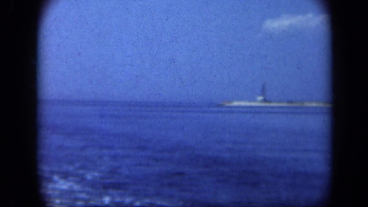 Distant Statue of Liberty across blue water with rounded film-frame edges.