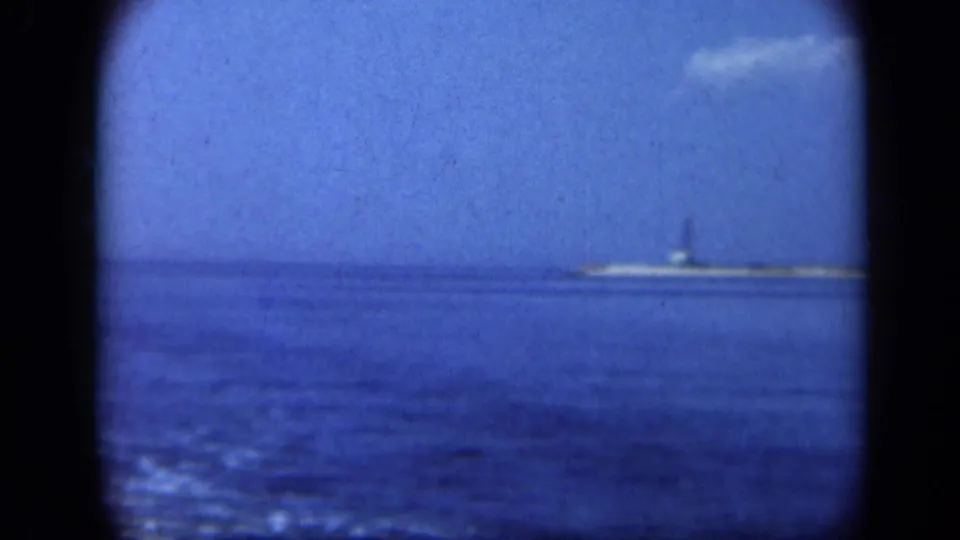 1948 Long Island home-movie frame showing the Statue of Liberty far across blue water under a bright sky.