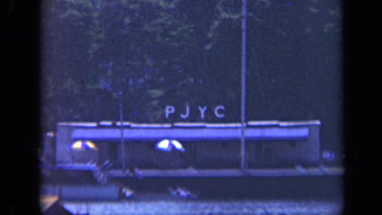 Lit barge with PJYC lettering on a dark waterfront.