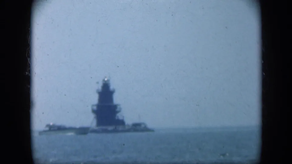 1948 Long Island home-movie frame showing a distant naval-looking vessel or towered structure on open water.
