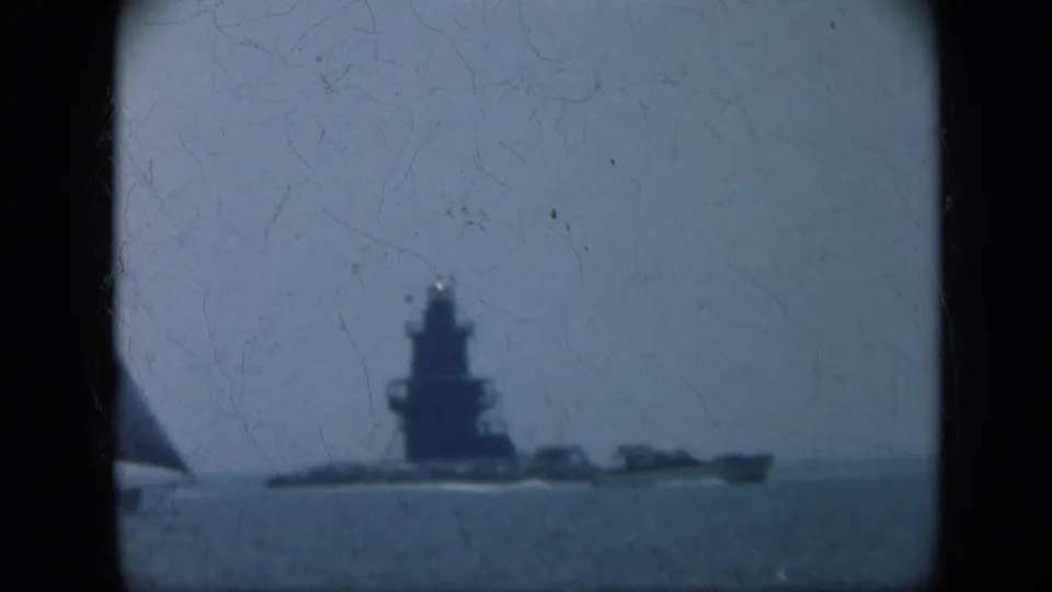 A naval ship moves across Long Island waters in 1948 as part of a sailboat enters the left edge of the 8mm frame.
