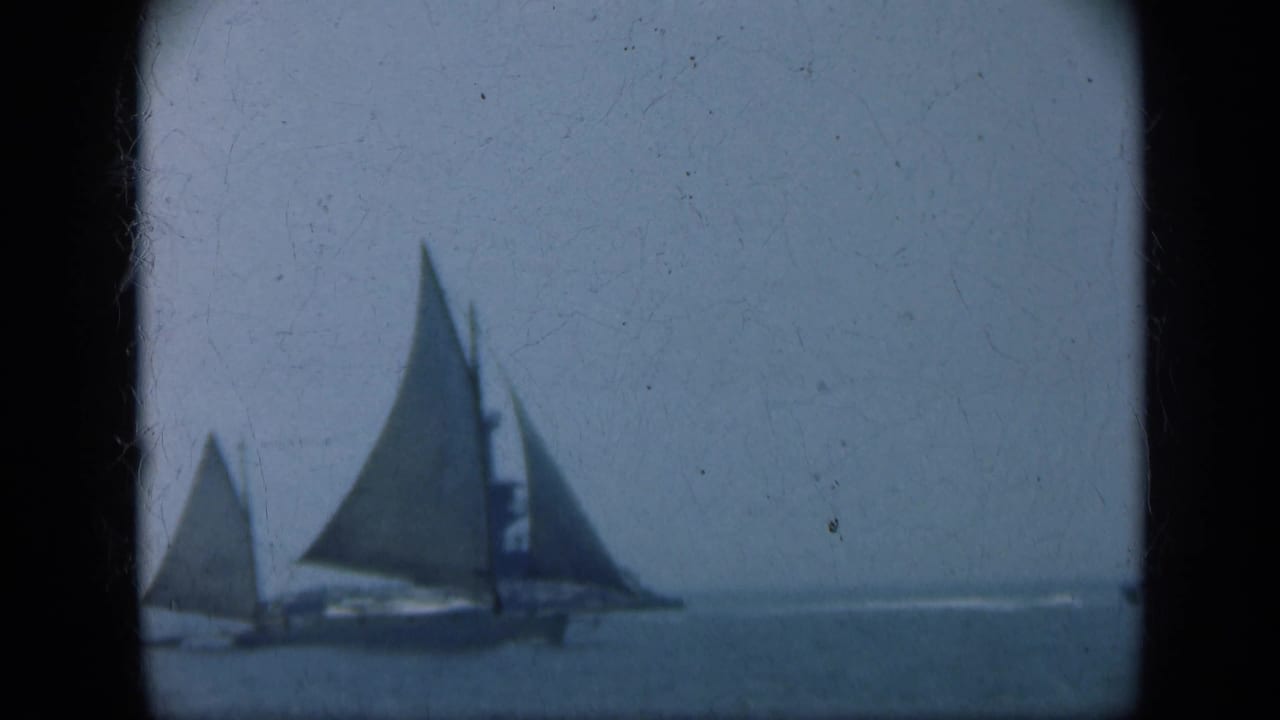 1948 Long Island 8mm frame showing two sailboats on open water with a distant lighthouse or tower under a hazy sky.