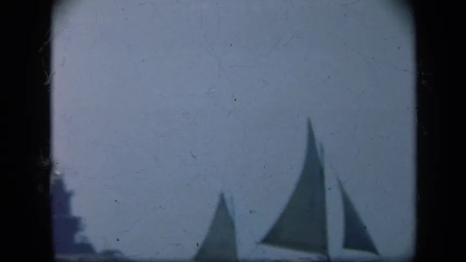 1948 Long Island 8mm frame with cropped sailboats on calm water, a lighthouse partly visible at the far left edge, and hazy sky.