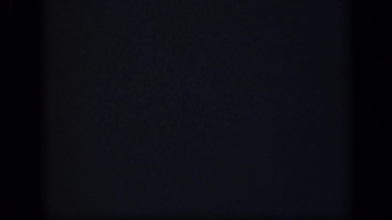 Mostly dark blank film frame with faint blue-gray grain and black frame borders.