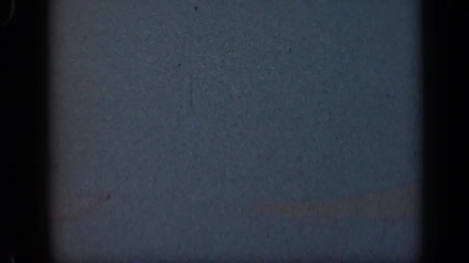 Blank blue-gray 8mm frame from the 1948 Long Island clip with visible grain, dust, and dark gate-like borders.