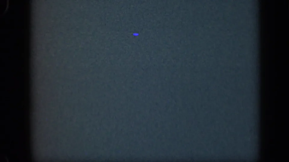 Underexposed 8mm frame from a 1948 Long Island home movie, showing mostly dark blue-green texture before the shoreline view appears.