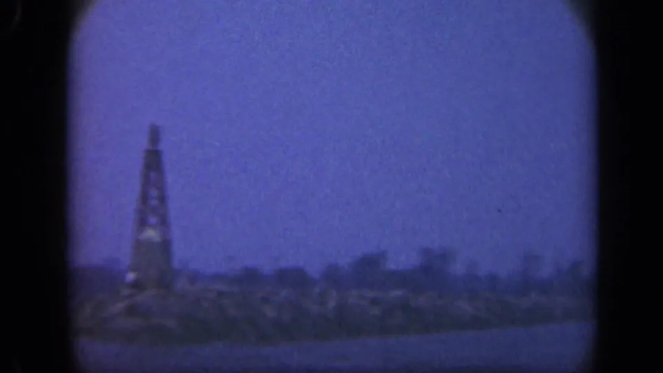 Blue-tinted 1948 Long Island sea view with a distant rocky shoreline and a tall tower-like structure near the water.