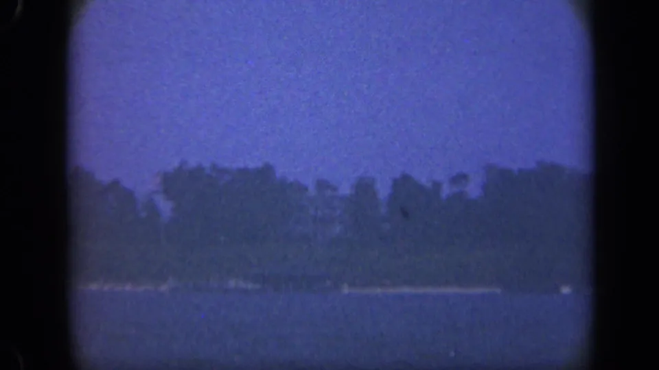 1948 Long Island landscape frame with water, a pale strip of shoreline, and trees under a blue overcast sky.