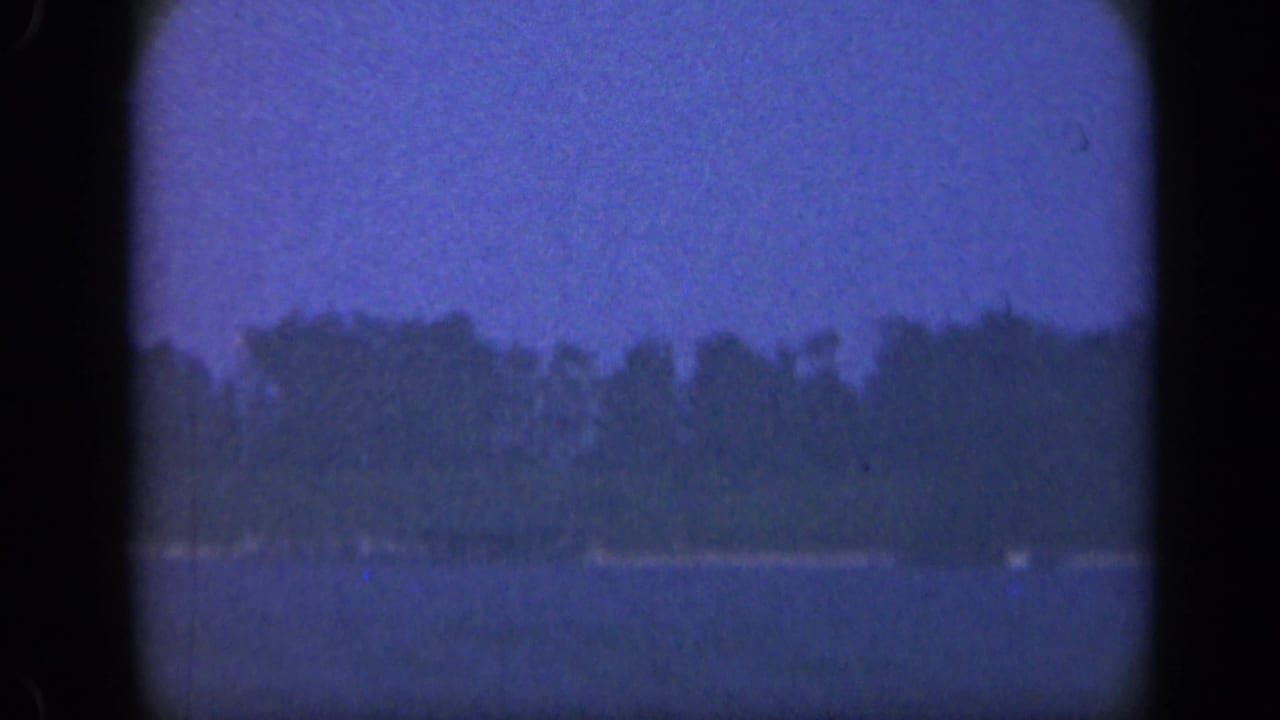 Blue-toned bay water facing a dark tree-lined shore through rounded 8mm frame edges.