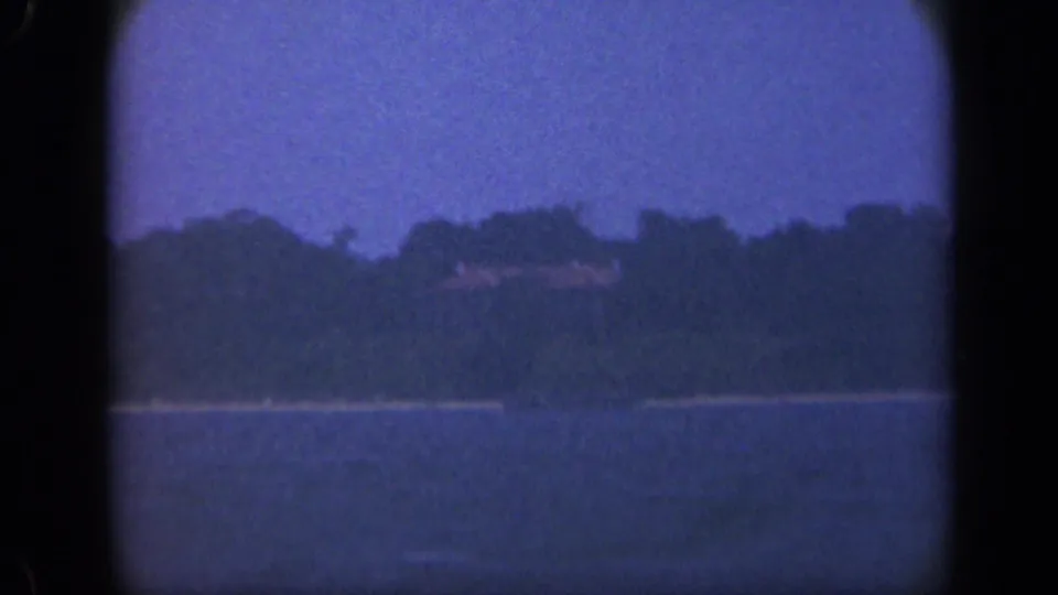 1948 Long Island bay view showing open water, trees, and faint shoreline buildings in grainy 8mm color.