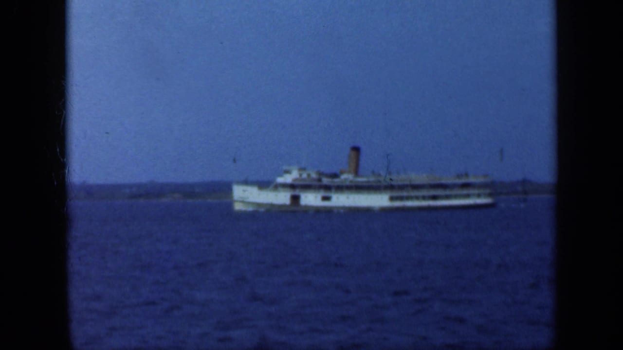 White passenger steamship on blue water beneath a clear sky.