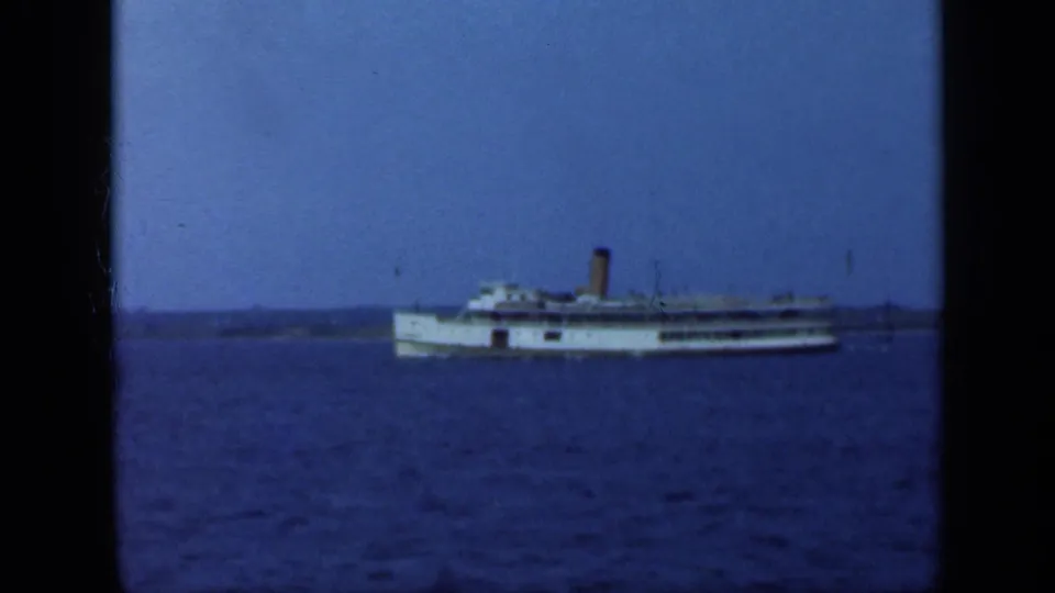 A distant white passenger steamship crosses blue water near Long Island in 1948 home-movie footage.