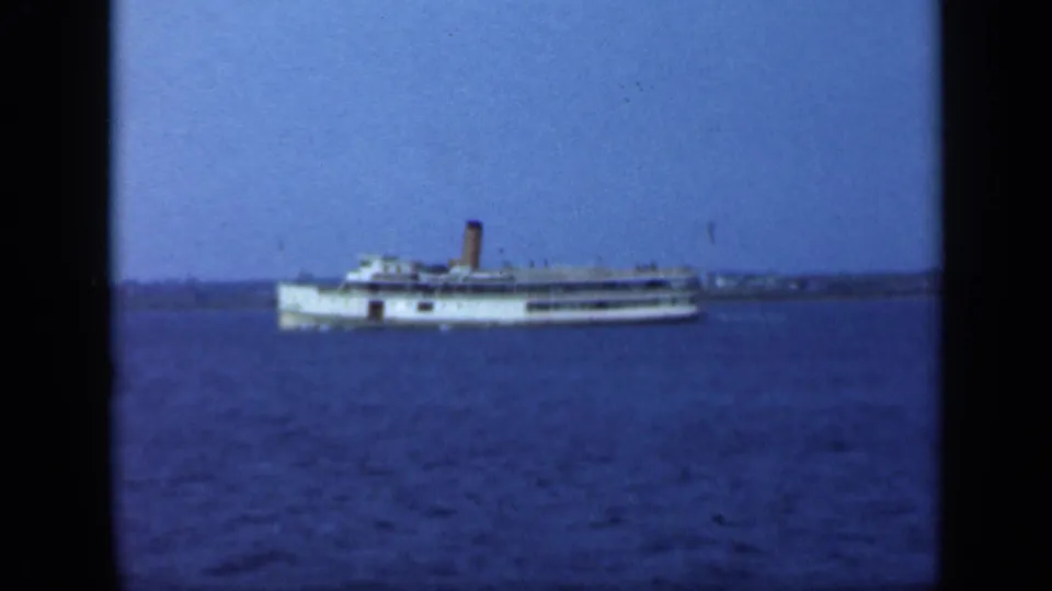 A 1948 Long Island home-movie frame shows the white passenger steamship lower in frame over textured blue water.