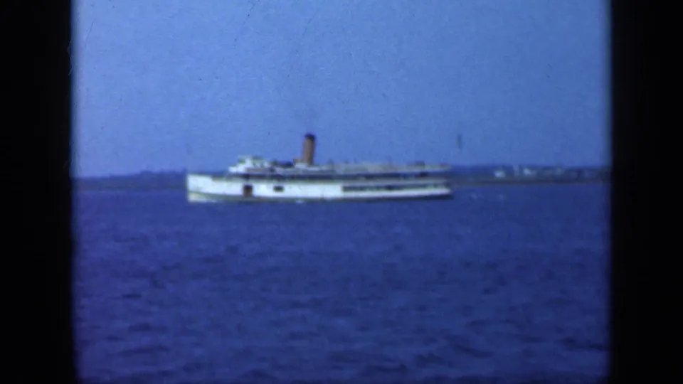 The passenger steamship appears farther across the water, with shoreline details faintly visible behind it.