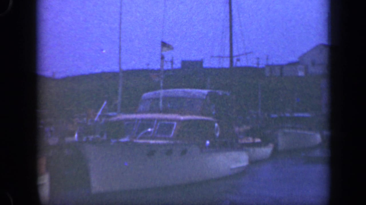 Docked boats and masts along a blue-tinted waterfront.